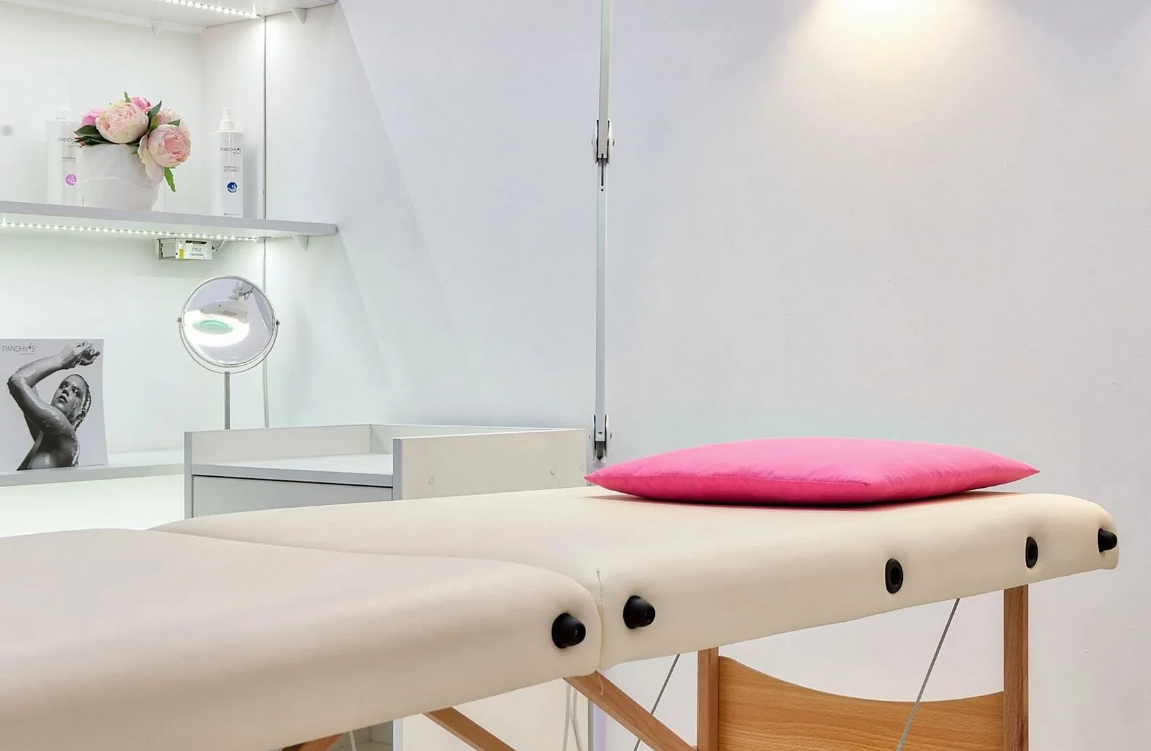 Treatment table with a pink cushion in a bright white room