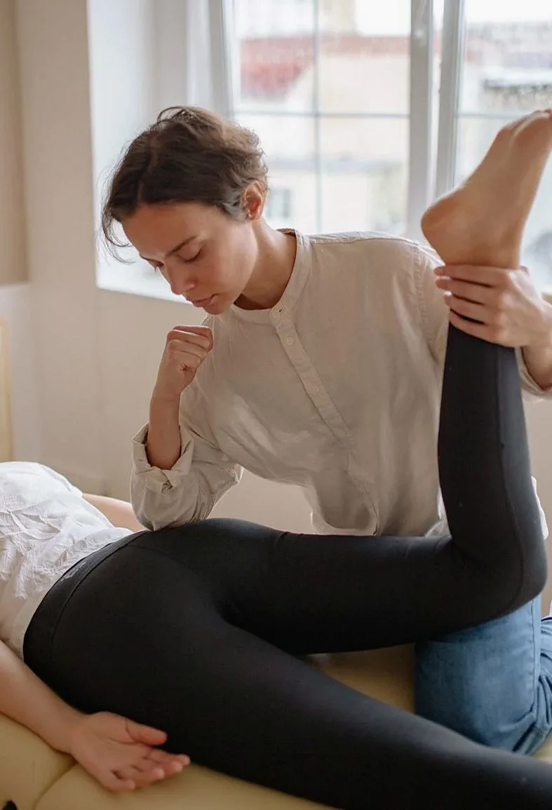 Practitioner stretching a client's leg on a treatment table